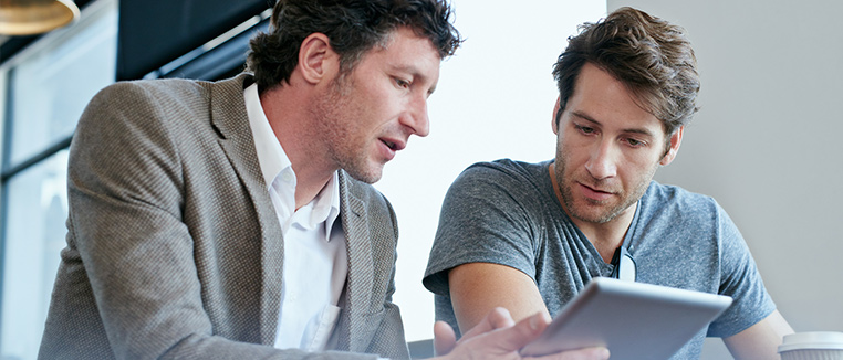 Two colleagues use a tablet for their work